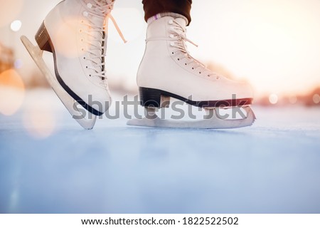White figure skates on winter ice rink with blurry bokeh background.