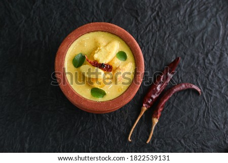 Mango and jackfruit seed curry, Chakkakuru Manga curry spicy Kerala food prepared use coconut and jack seed in terracotta or clay pot on dark black background South India. Top view of Indian veg food.