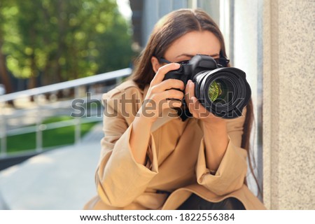Private detective with camera spying near building on city street