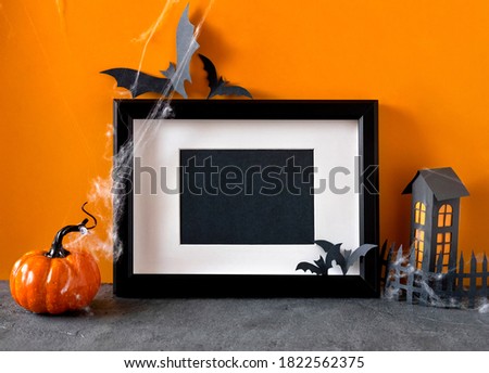 Happy halloween holiday concept. Black frame on orange background. Halloween decorations, pumpkins, bats, black frame. Halloween party greeting card mockup with copy space. 