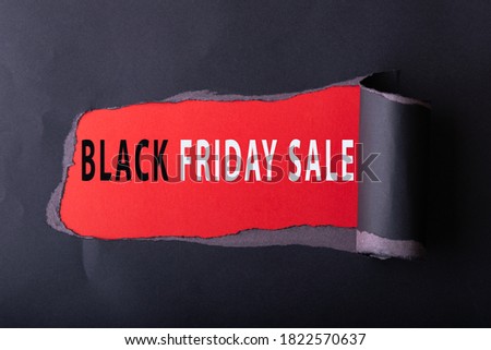 Black torn paper with  des scription BLACK FRIDAY DAY SALE on red background for background. Black Friday concept