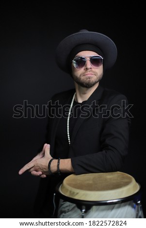 Portrait of a percussionist. Handsome man in a hat and glasses.Man in glasses on a black background.A guy in a hat on a black background in glasses.Drummer in a hat and glasses