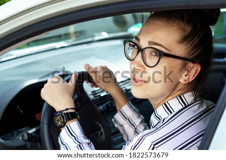 beautiful successful smiling rich business woman in white suit sitting in gray car salon , wearing glasses talking on phone on a parking , prosperous business lady style Lady is driving a car for work