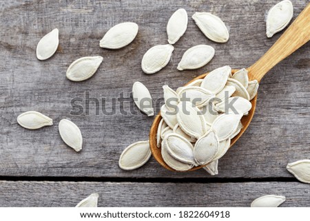 Unpeeled pumpkin seeds in a wooden spoon. Top view.