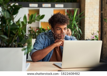 Photo of concentrated african entrepreneur freelancer using computer while have work online at the table in loft