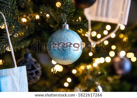 Christmas decoration hanging in a Christmas tree with face mask for Coronavirus, Covid-19 in 2020 and the words Merry Christmas closeup
