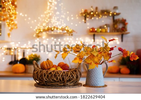 Autumn kitchen interior. Red and yellow leaves and flowers in the vase and pumpkin on light background Royalty-Free Stock Photo #1822629404