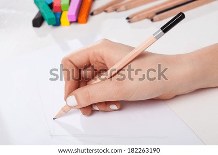 A closeup of a hand drawing a sketch with a pencil