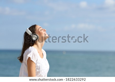 Profila of a happy woman breathing fresh air with headphones listening to music on the beach Royalty-Free Stock Photo #1822633292