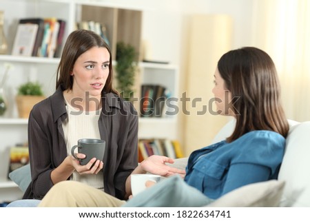 Serious friends talking sitting on a couch in the living room at home  Royalty-Free Stock Photo #1822634741
