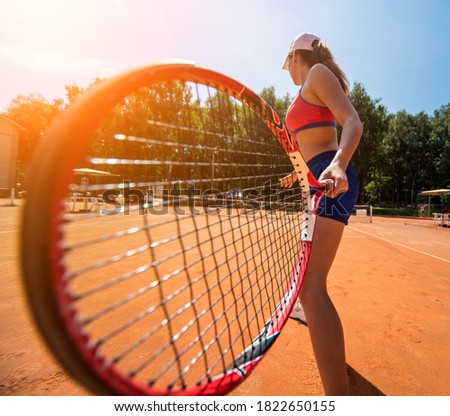 Young athletic woman playing tennis on the court.