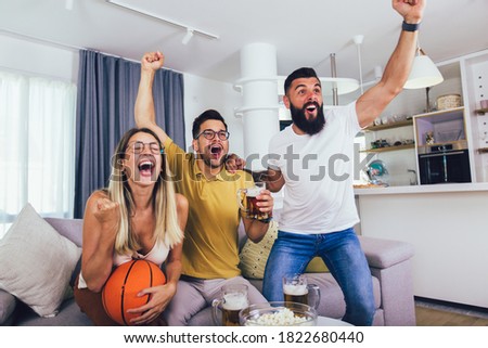 Happy friends or basketball fans watching basketball game on tv at home and celebrating victory at home.Friendship, sports and entertainment concept.