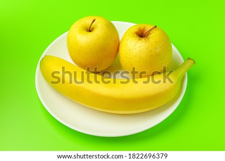 banana and Apple on a green background close-up. isolate