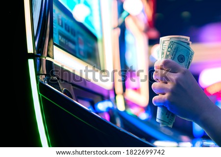 Slot Machine Play Time. Female Gambler Hand hold money bill ready to win the game with one best shot casino close up Royalty-Free Stock Photo #1822699742