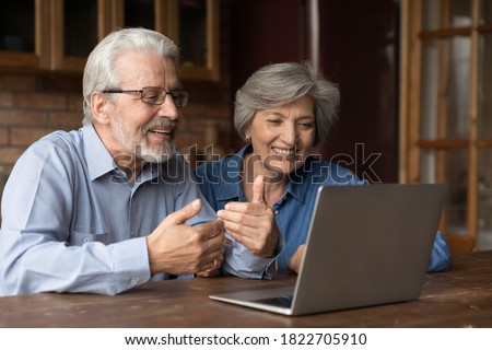 Smiling mature Caucasian couple husband and wife look at laptop screen have webcam virtual online conference. Happy senior man and woman speak talk on video call using modern computer gadget. Royalty-Free Stock Photo #1822705910