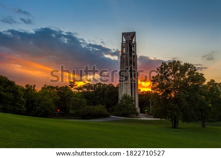 Sunbeams bursting through clouds at sunset behind the Carillon bell tower in Naperville, Illlinois just west of Chicago Royalty-Free Stock Photo #1822710527