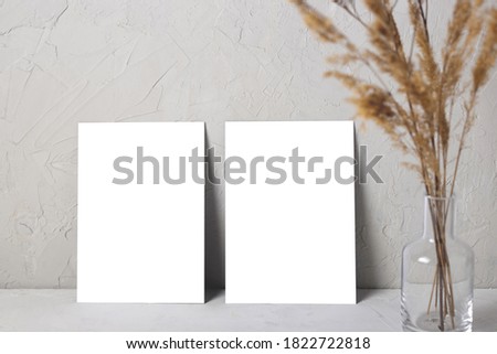 Mock up of two postcard on a gray background next to a bouquet of summer dried flowers