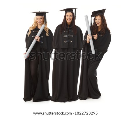 Three pretty female graduates in academic dress smiling happy, holding diploma.
