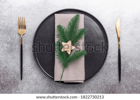 Christmas table setting with black ceramic plate, napkin, cutlery on stone background. Top view. Copy space - Image