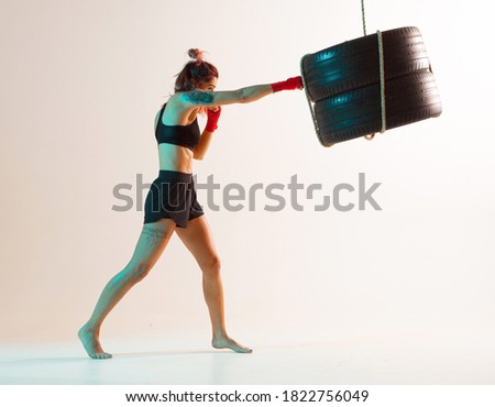 Cool female fighter trains jab on beige background in neon light. Women's sport and motivation concept