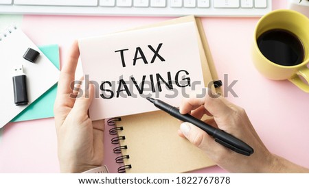 Notepad with text Tax Savings, paper clips, blue pen on financial diagrams. Business concept