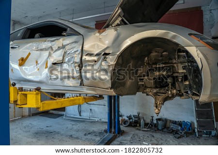 Broken or damaged sport car after road accident or crash in garage repair service shop Royalty-Free Stock Photo #1822805732
