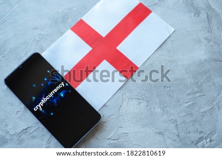 Cryptocurrency and government regulation, concept. Modern economy, smartphone with bitcoin sign on the screen on the background of the flag of England
