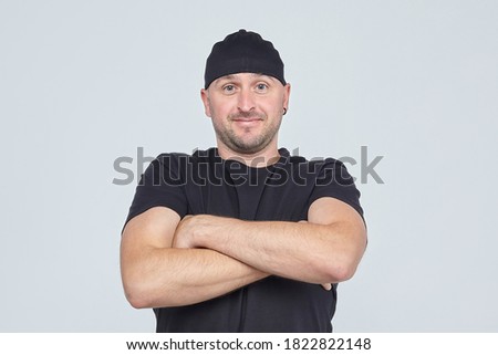 grown man in a black cap and t shirt crossed his arms over his chest