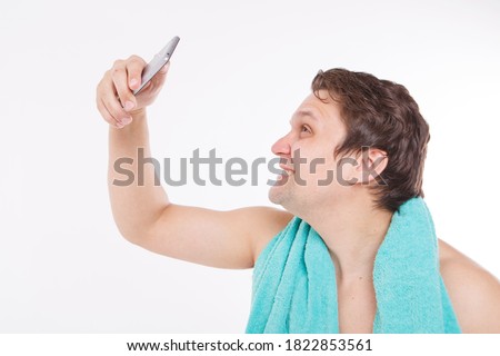 the guy takes a selfie after morning procedures. A man looks at the phone camera. Smooth-shaven face. Blue towel around her neck. Man and modern technologies. the conversation via video link