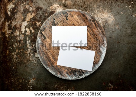 Photo of blank white business cards on a dark wooden cutting board circle. Blank template for brand identity mock-up design, food theme. Presentation and portfolio template