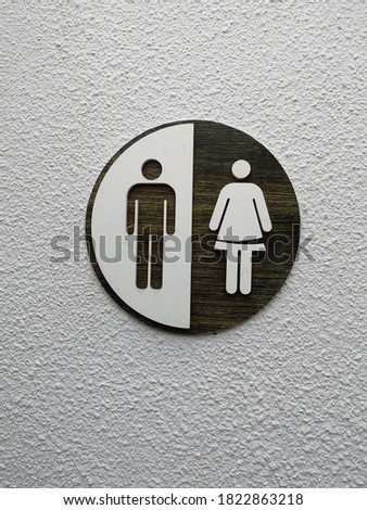 Female and male toilet sign. The circular symbol of the toilets on white cement wall in the hotel.