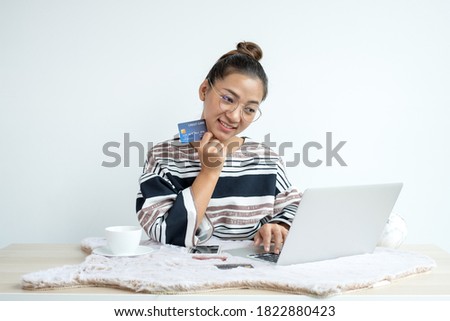 The Asian businesswoman's hand is holding a credit card and using a laptop for online shopping and internet payment in the office.