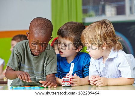 Three children in kindergarten playing with building blocks and cars Royalty-Free Stock Photo #182289464