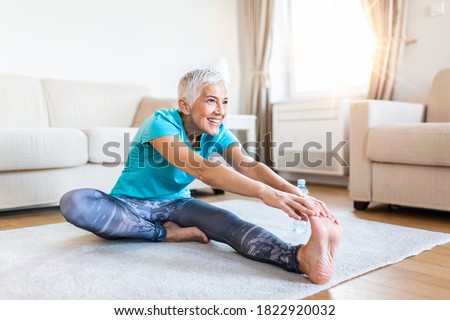 senior woman doing warmup workout at home. Fitness woman doing stretch exercise stretching her legs,quadriceps .Elderly woman living an active lifestyle.