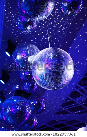 Light and music disco ball on a blue background. A rotating disco ball in a nightclub with sparkling effects. Vertical photo