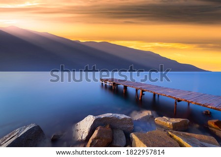 View of the mountain, sea and pier at sunset. sunset view from mediterranean coves. Photo of the sea and wooden pier taken with long exposure technique. Gokova bay, Mugla, Turkey.