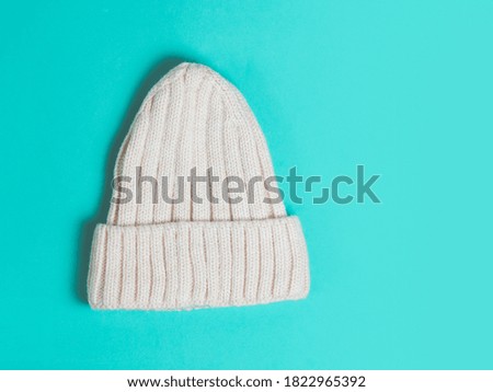 Warm woolen knitted hat turquoise colored background. Festive christmas wear.