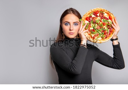Beautiful woman holds whole big pizza over bright background. Fast food, junk food concept. Pizza restaurant advertisment concept, copy space banner.