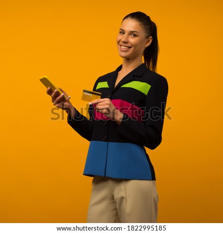 Lady buying online with a credit card and smart phone on yellow background - image