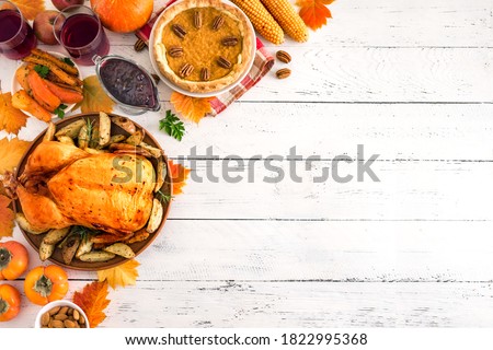 Thanksgiving dinner with chicken, cranberry sauce, pumpkin pie, wine, seasonal vegetables and fruits on white wooden table, copy space. Traditional autumn holiday food concept.