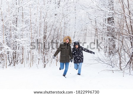 Happy couple walking through a snowy forest in winter