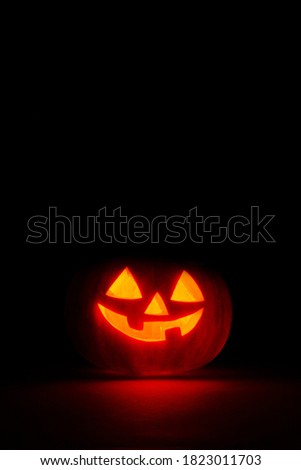 halloween pumpkin in the dark with candle inside, black background with copy space