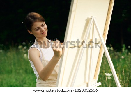 Woman in nature paints a picture on an easel art
