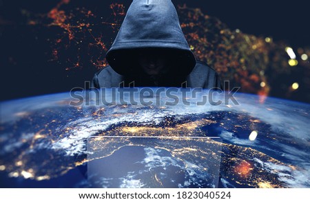Unrecognizable hacker using laptop over Earth background. Toned image double exposure. Elements of this image furnished by NASA
