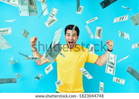 Happy excited man standing under money rain banknotes falling down. Success, business, and fortune concept