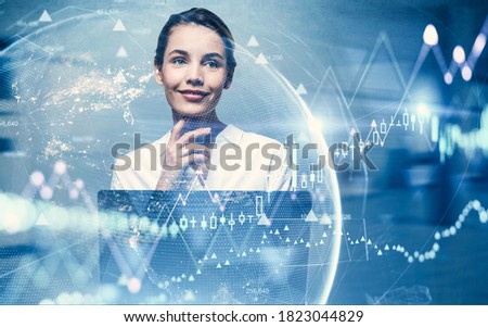 Cheerfu young businesswoman using laptop in blurry office with double exposure of digital graphs. Toned image. Elements of this image furnished by NASA