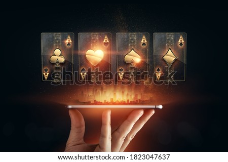 Creative background, online casino, in the male hand a smartphone with playing cards, black-gold background. Internet gambling concept. Copy space