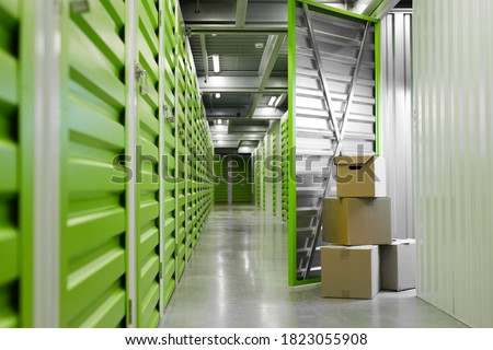 Background image of green self storage facility with opened unit door and cardboard boxes, copy space Royalty-Free Stock Photo #1823055908