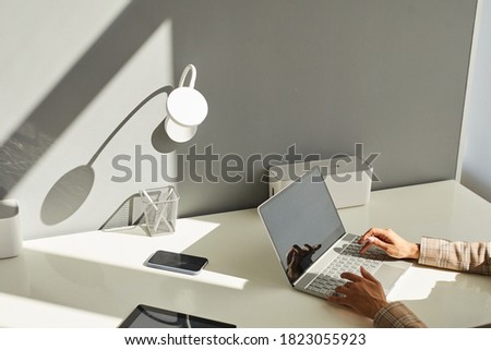 Minimal background image of unrecognizable woman using laptop on white workplace desk with focus on elegant female hands typing on keyboard in sunlight, copy space Royalty-Free Stock Photo #1823055923