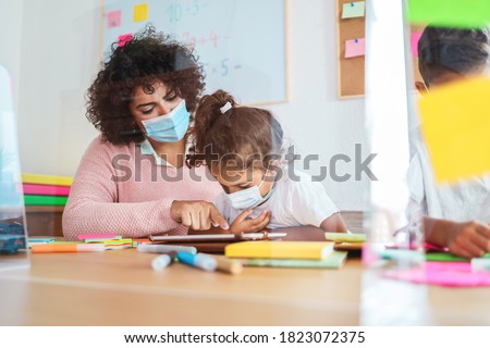 Teacher using tablet with children in preschool during coronavirus outbreak - Focus on woman's hand Royalty-Free Stock Photo #1823072375